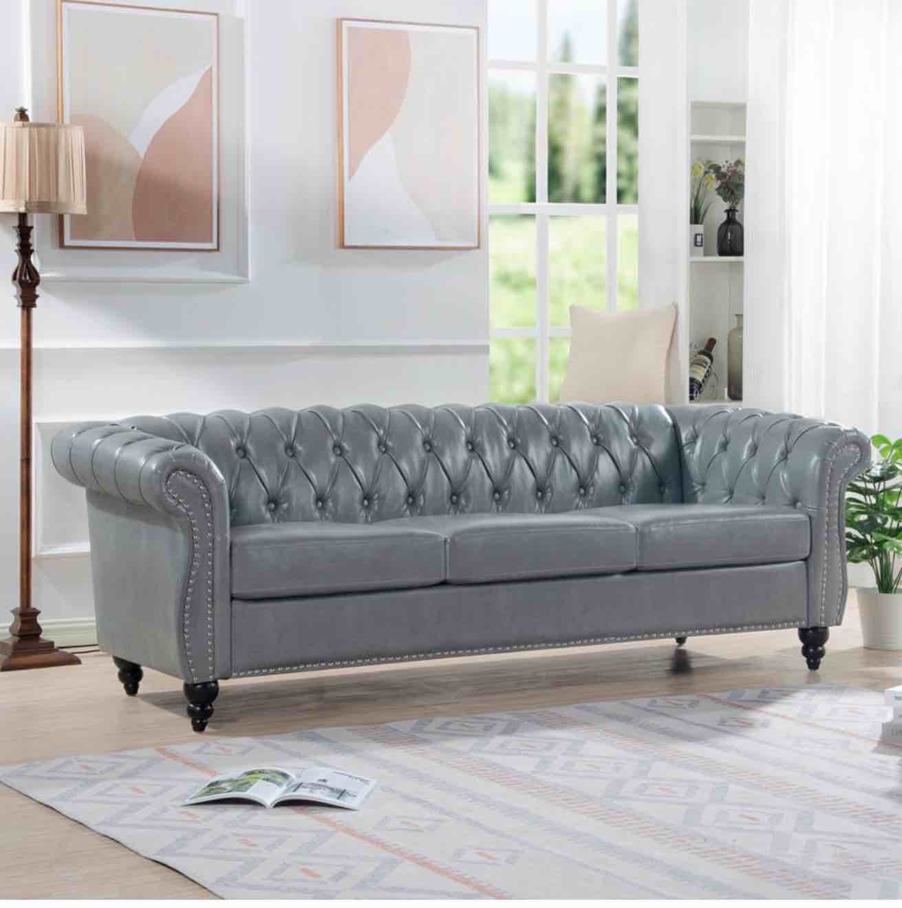 Condition photo showing New/Like New for 84.5” chesterfield rolled arm 3 seater couch with gray tufted upholstery, nailhead accents, overall dimensions 84.65'' w x 32.09'' d x 28.35'' h, legs of couch have a few small scuffs(pictured)