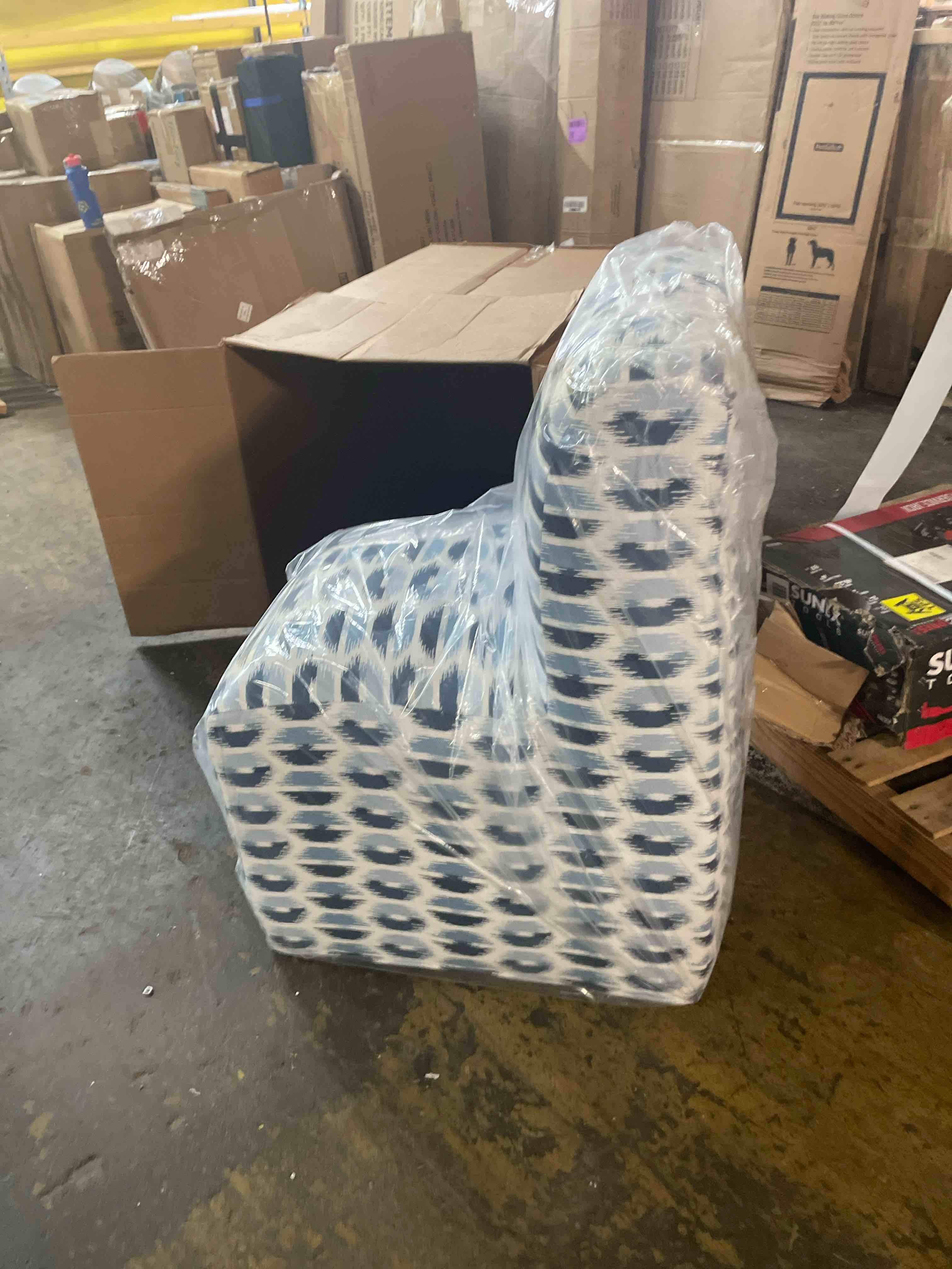 Condition photo showing New/Like New for wrapped accent chair features a blue and white patterned upholstery with a curved, armless silhouette.