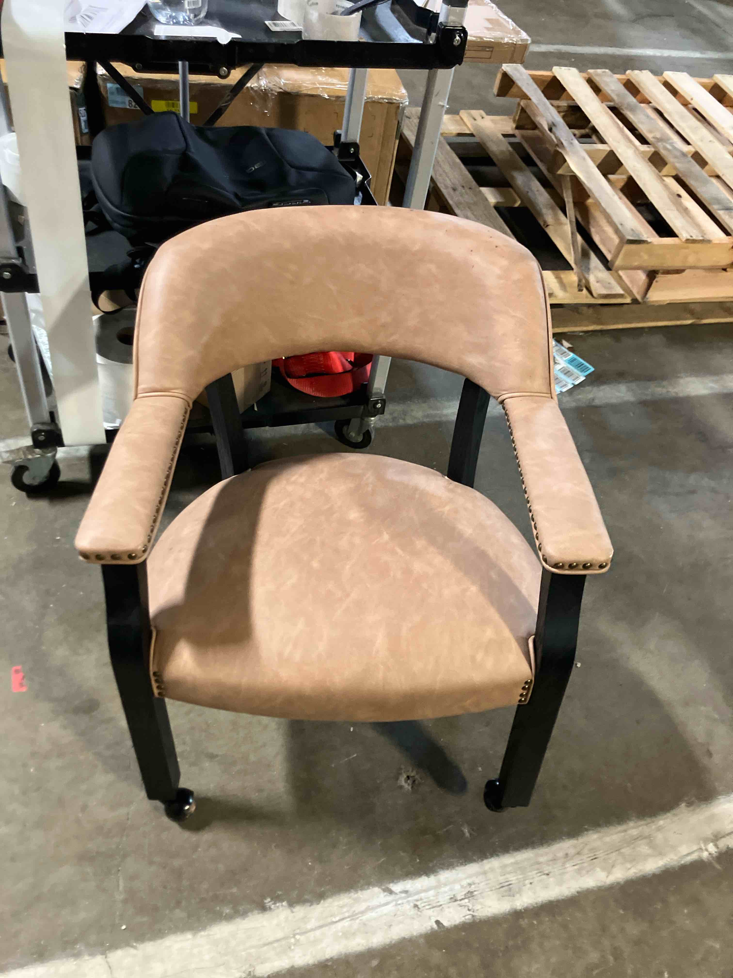 Condition photo showing As Is for Steve Silver Furniture Rylie Dining Upholstered Arm Chair, Castered Captians Chair, Vegan Leather, Nailhead Trim, Office/Dining/or Living Areas, 300lb Capacity, 25.75" L x 26.75" W x 30.75" H, Brown (Missinga wheel)