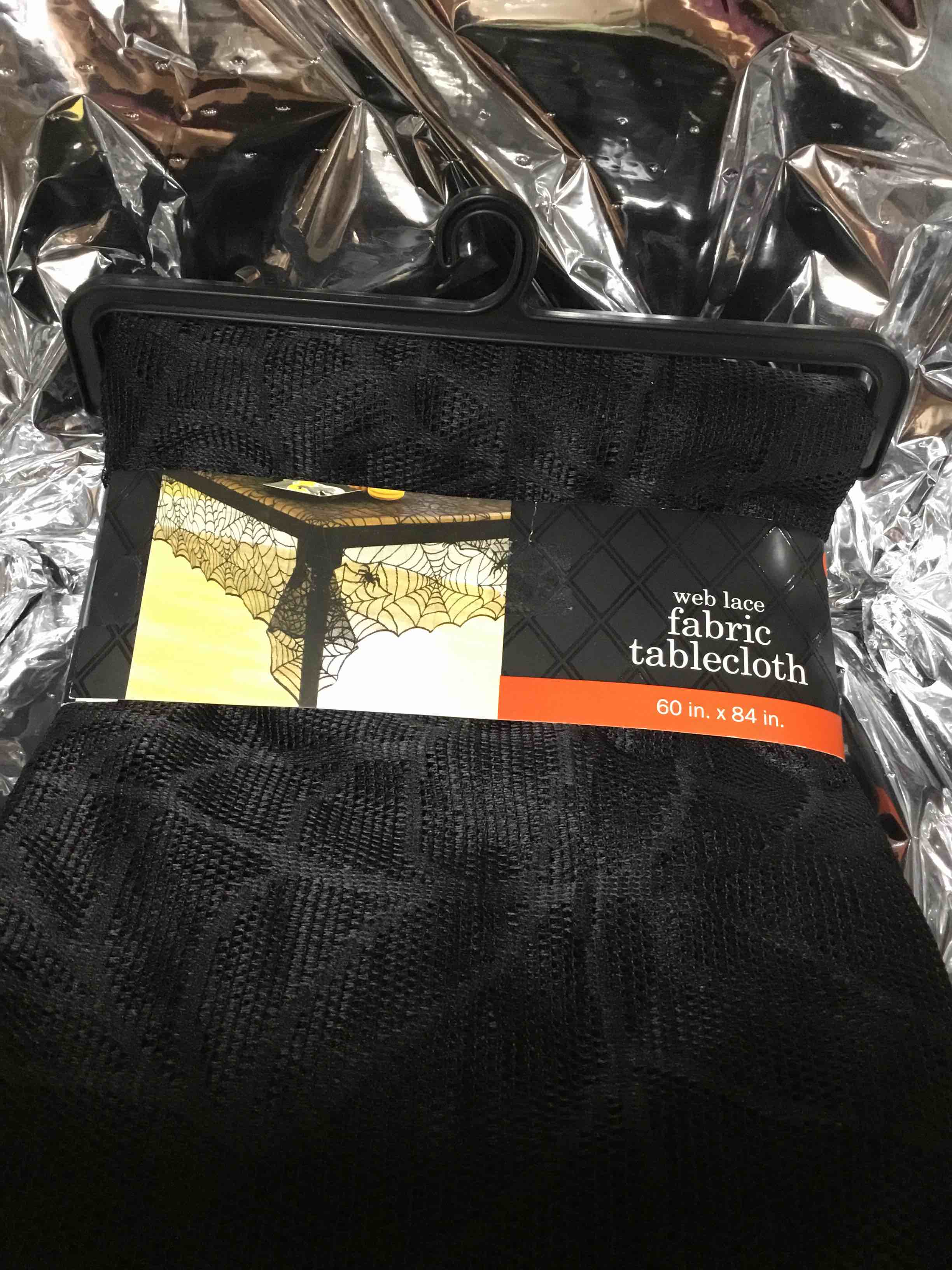 This is a black web lace fabric tablecloth, measuring 60 in. x 84 in., suitable for Halloween decoration. 