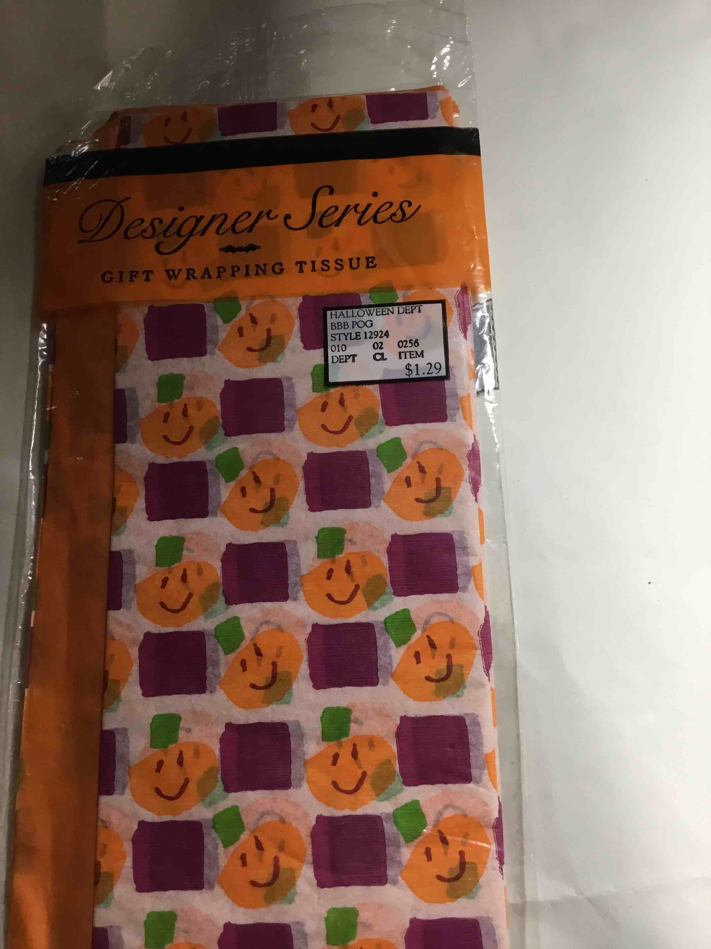 The tissue paper has a pattern of smiling pumpkins and purple squares.