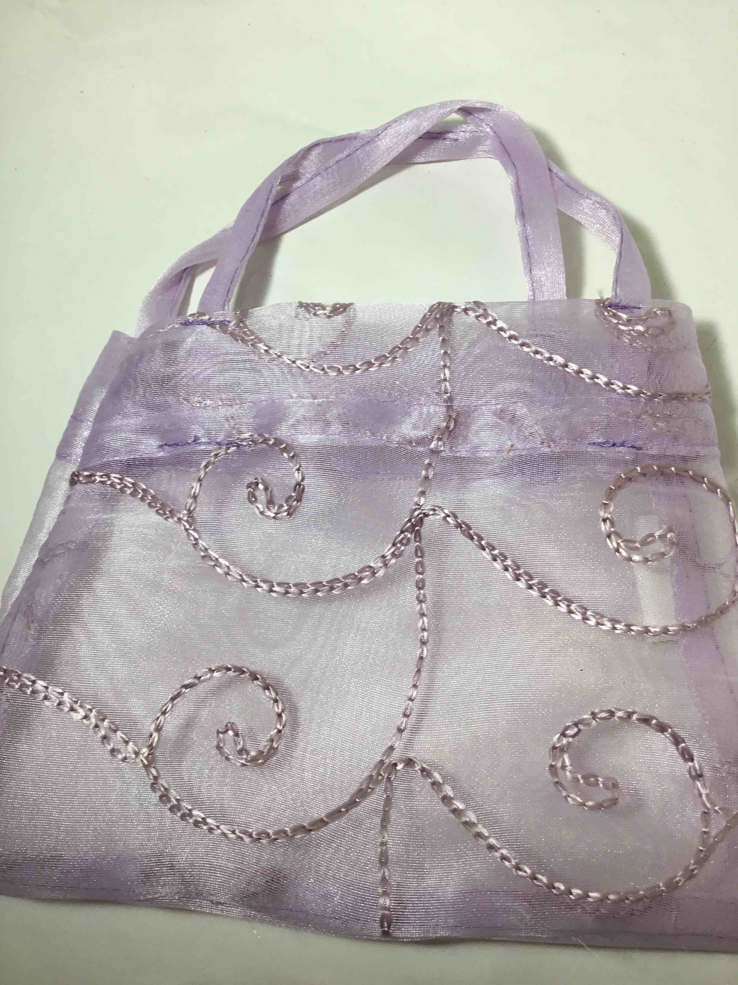 Lavender organza bag with embroidered swirls.