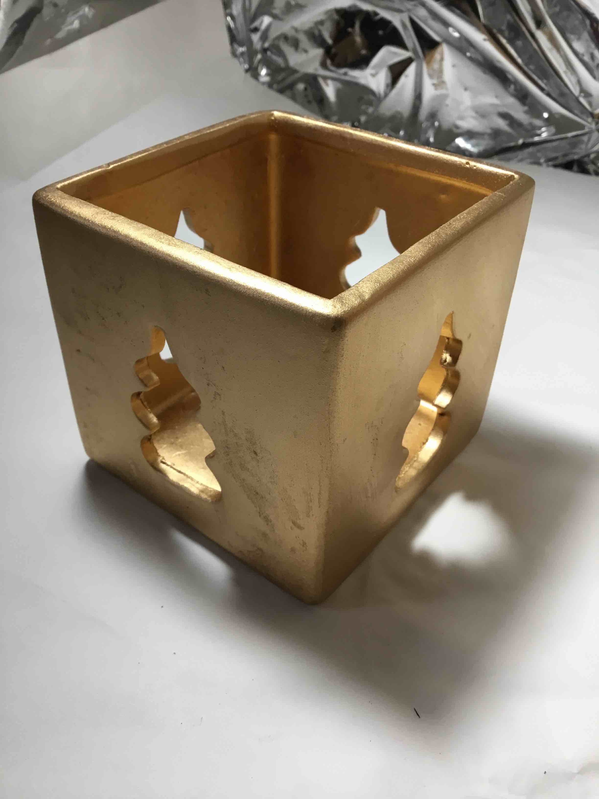 Gold-colored ceramic cube candle holder with tree cutouts.  