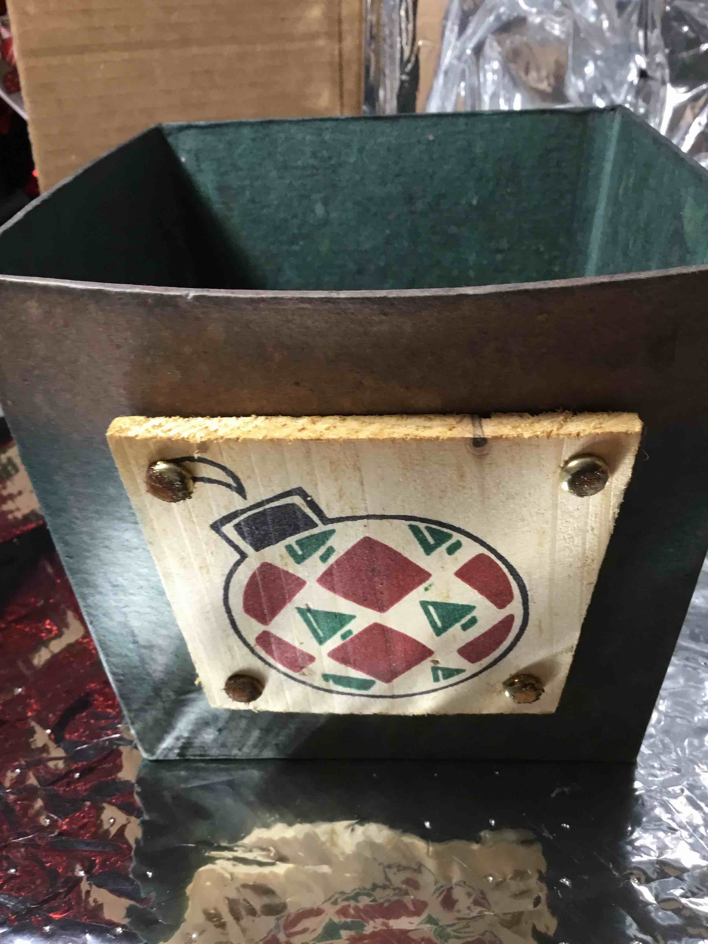 Christmas container or basket, papier-mâché with a green finish. It is decorated with a wooden plaque featuring a painted Christmas ornament design.