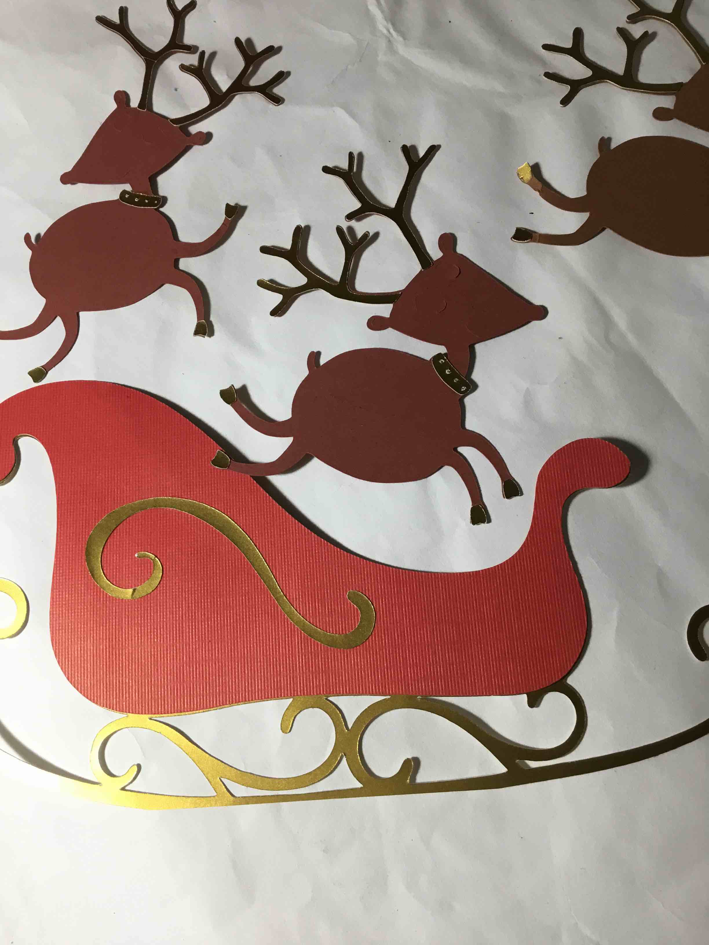 Die cut paper, sleigh, and reindeer’s gold trimmed