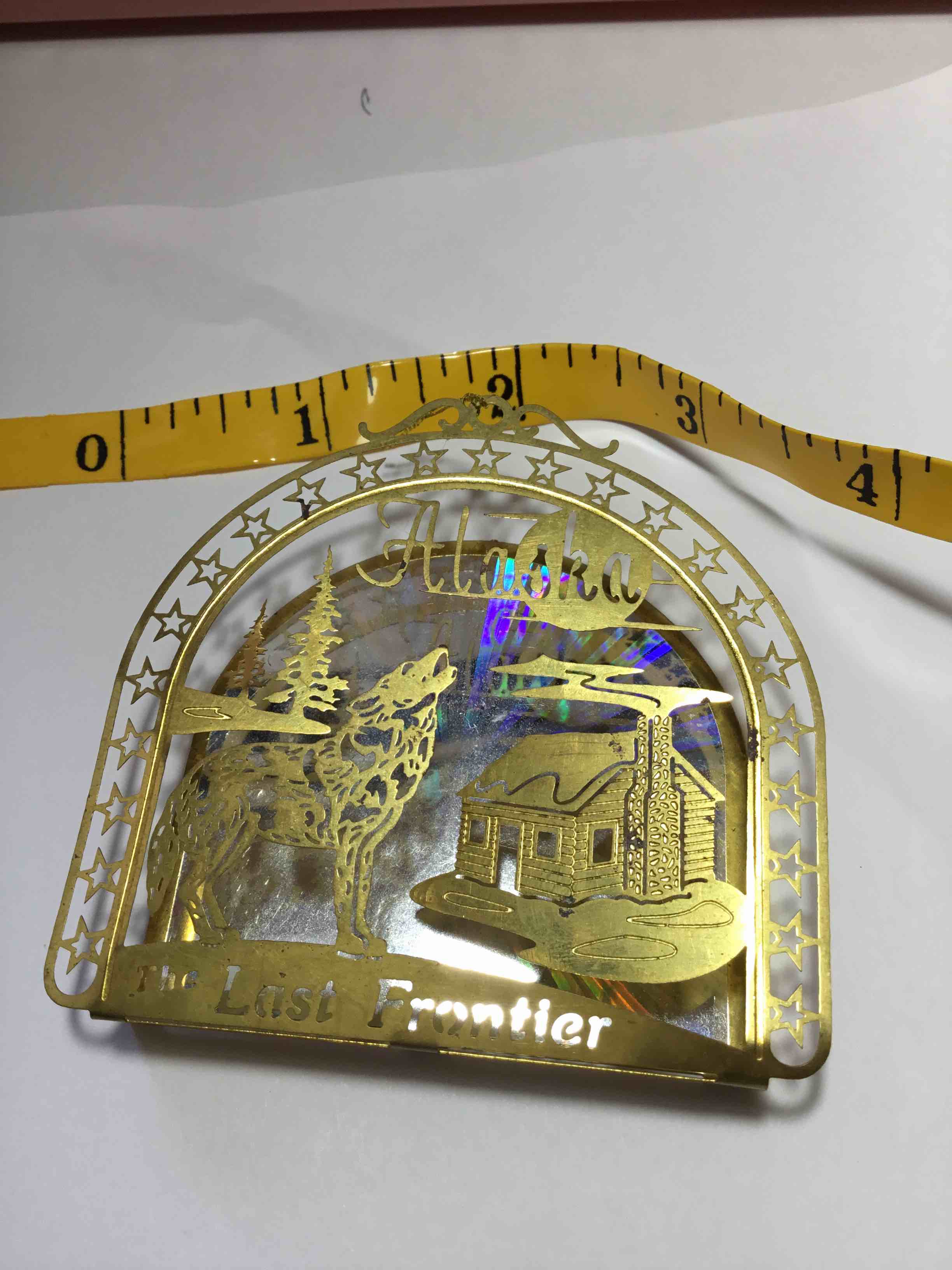 Alaskan-themed metal Christmas ornament with the text "Alaska" and "The Last Frontier" on it.