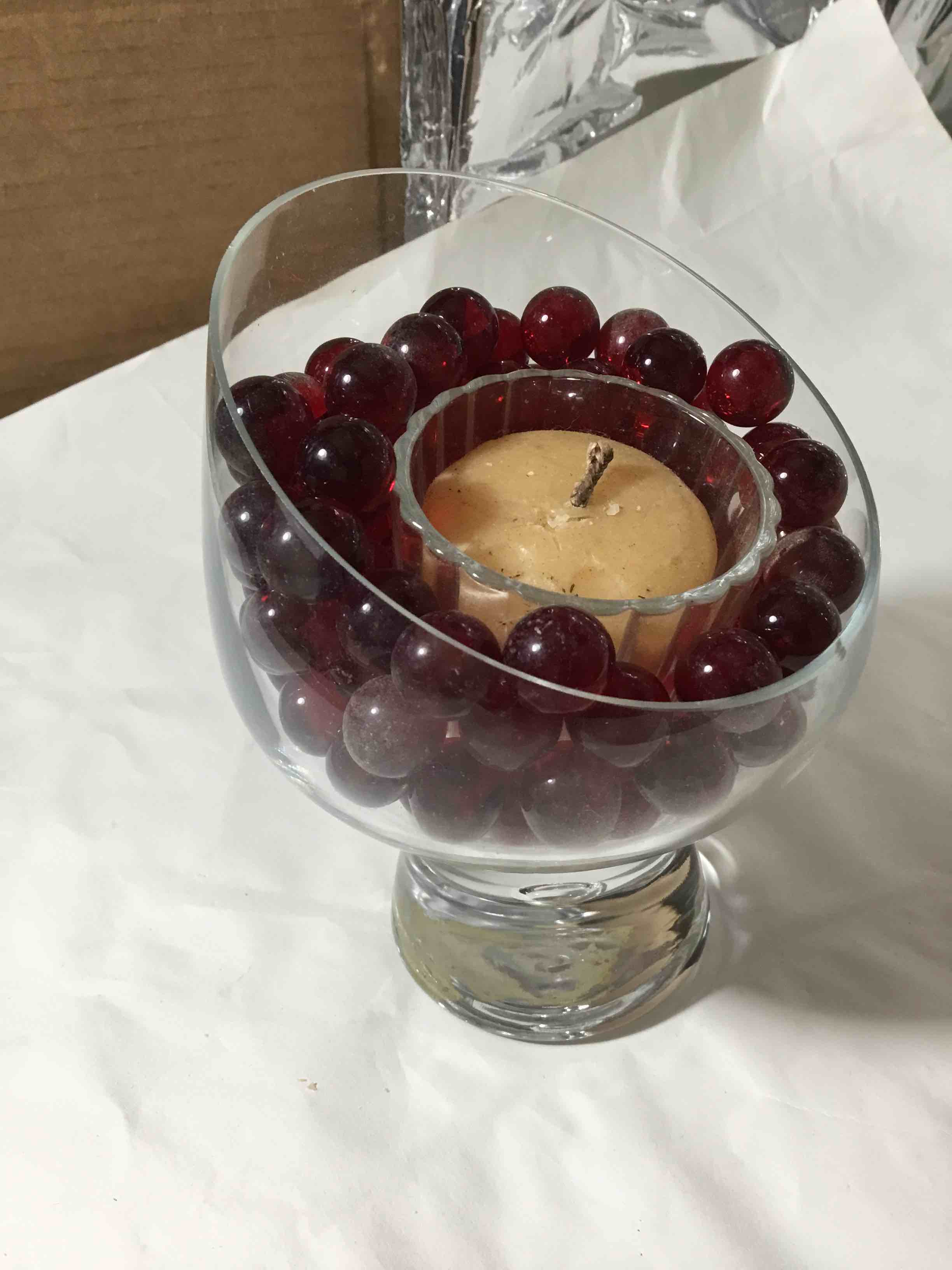 Condition photo showing As Is for Wine glass candle holder filled with red decorative beads and a tea light candle