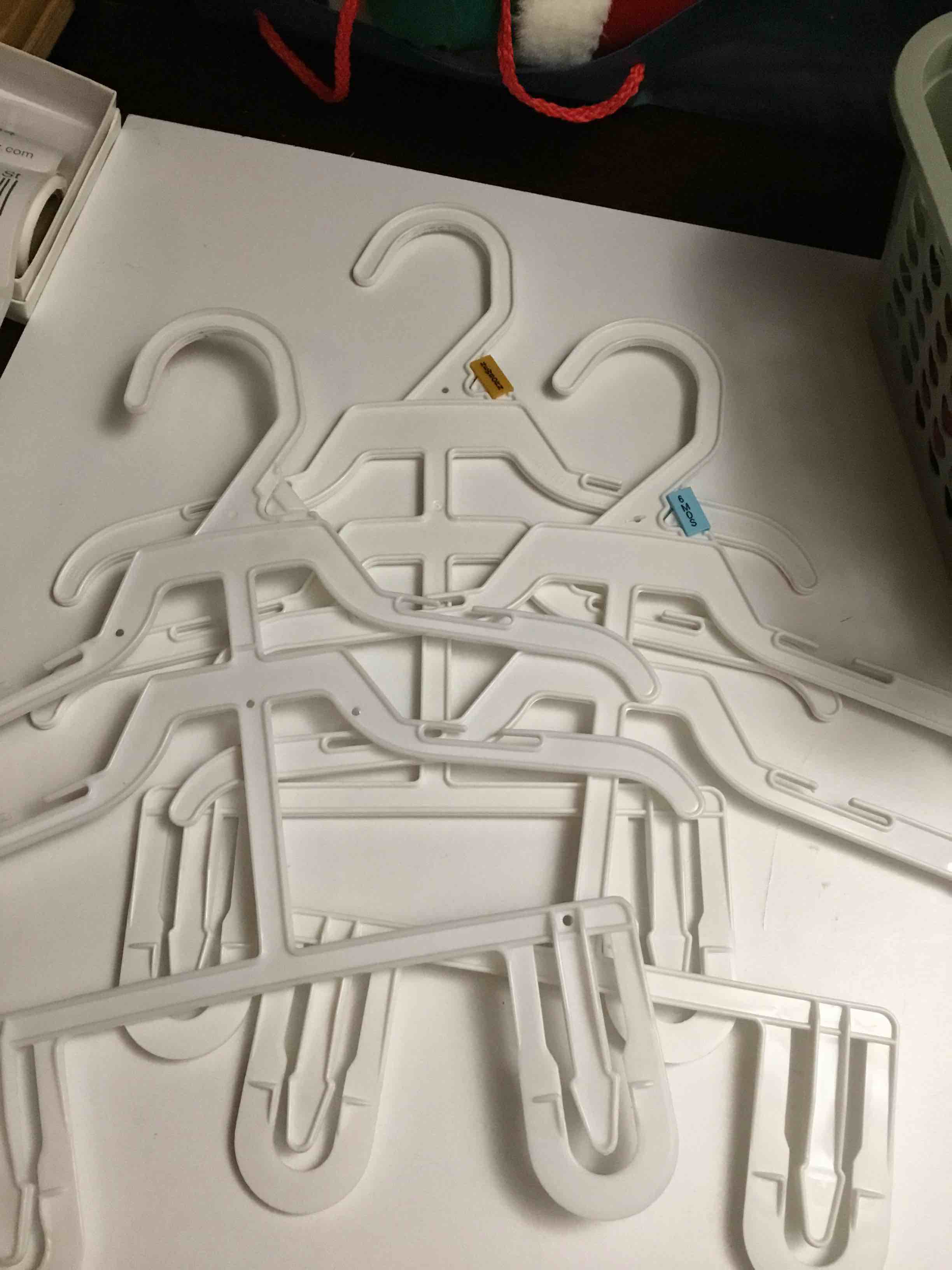 White plastic children's clothing hangers with clips for hanging both tops and bottoms. 