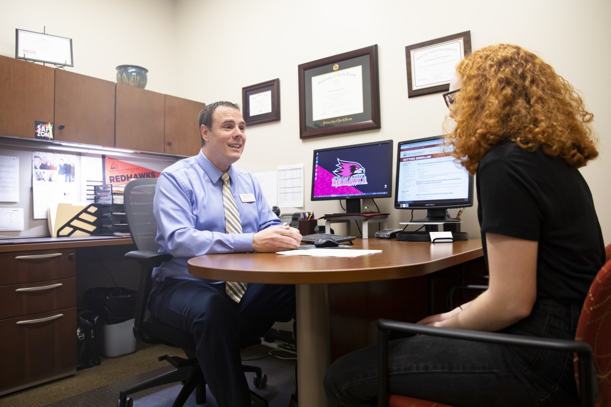 A student talking to an academic advisor in an office