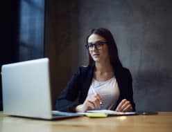 A woman looks at her computer while writing something down