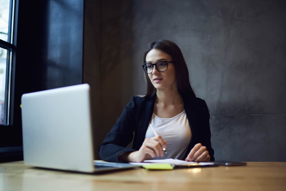 A woman looks at her computer while writing something down