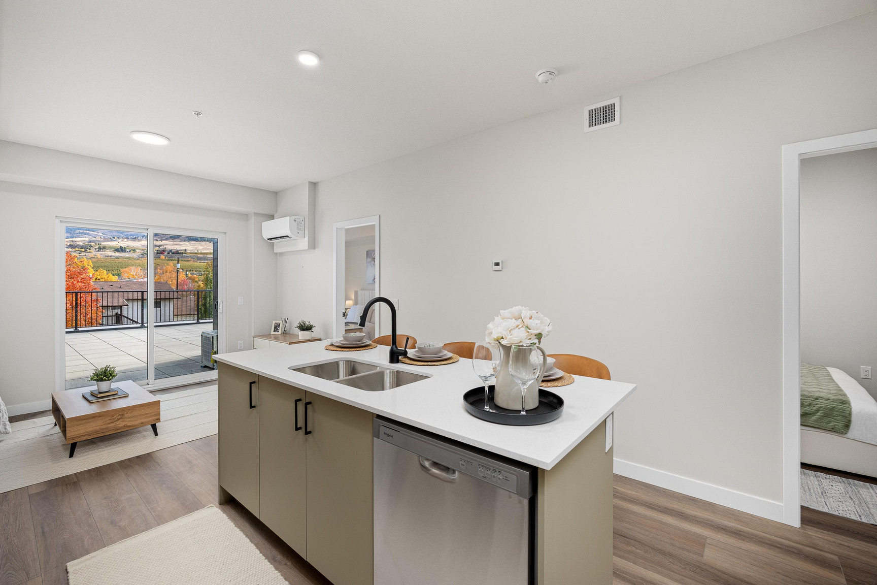Bright open-concept kitchen at Central Kelowna with pendant lighting, full-size fridge, and sleek finishes in a downtown two-bedroom apartment.