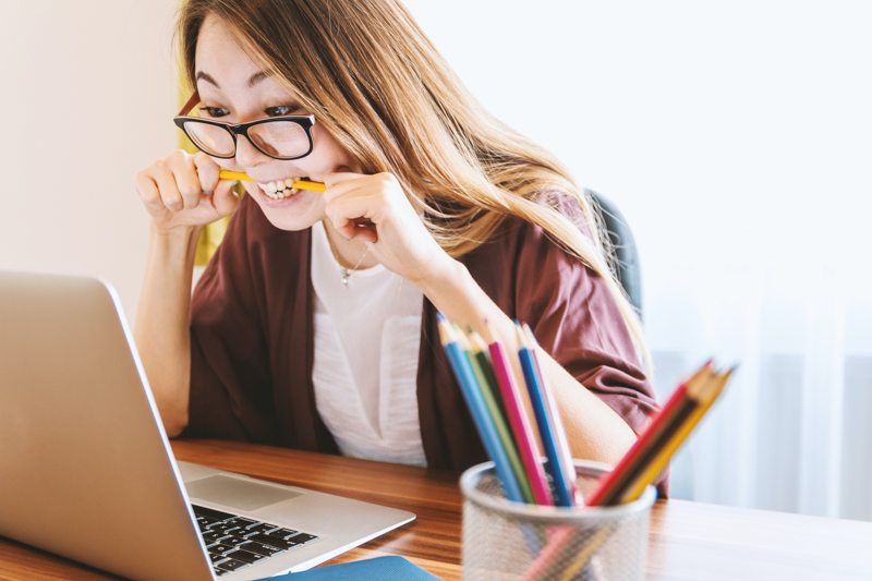 Stressed woman chewing on a pencil at her desk.