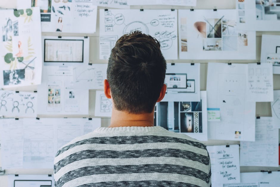 Guy starring at papers pinned to a wall.