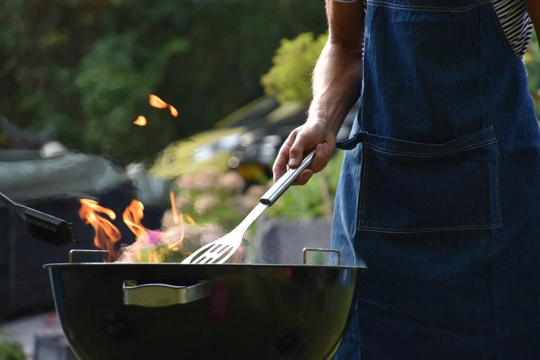 Man grilling food on a flaming BBQ