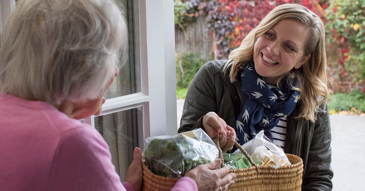 Good neighbour handing elderly neighbour groceries