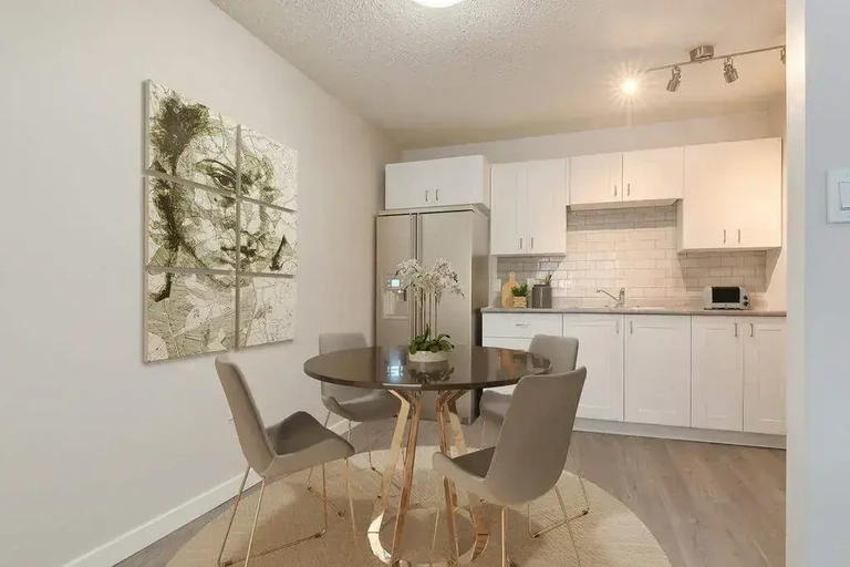 Dining area and modern kitchen with stainless steel appliances at Cotton Wood Apartments in Medicine Hat.