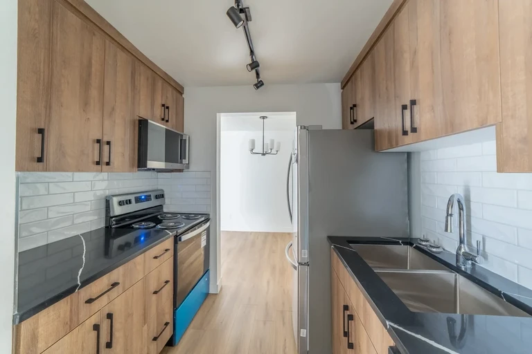 Galley style kitchen with stainless steel fridge and stove at Huntington Townhomes in Edmonton.