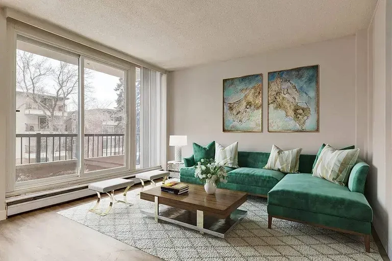 Sunlit living room with large windows at Alumni Apartments in Calgary.