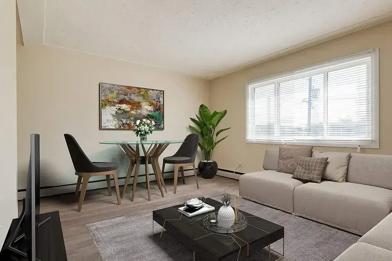 Sunlit living room with large windows at Chelsey Manor in Edmonton.