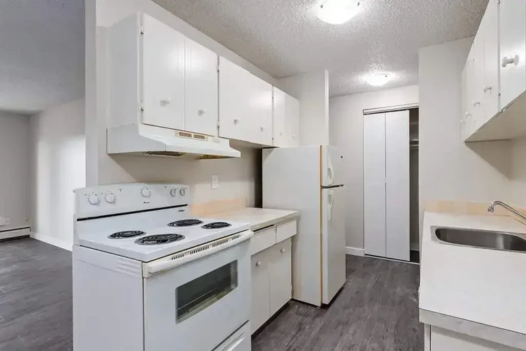 Galley style kitchen with appliances and access to living area at Flamborough Garden in Lethbridge.