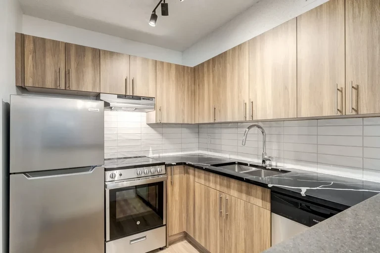 Contemporary kitchen with stainless steel appliances at Cedarvilla  Apartments in Calgary.