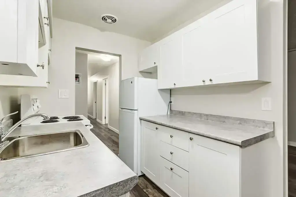 Galley style kitchen with appliances at Louise Apartments in Edmonton.