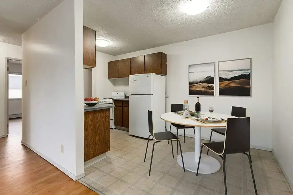 Galley style kitchen with appliances and dining area at Ruby Court in Lethbridge.