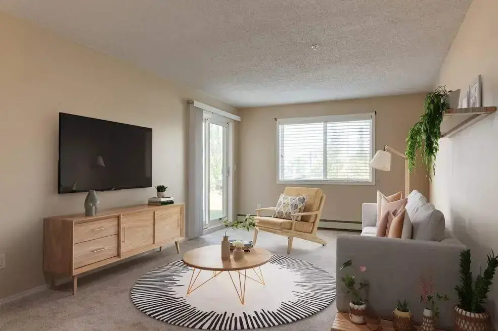 Sunlit living room with large windows at Amberwynd Apartments.