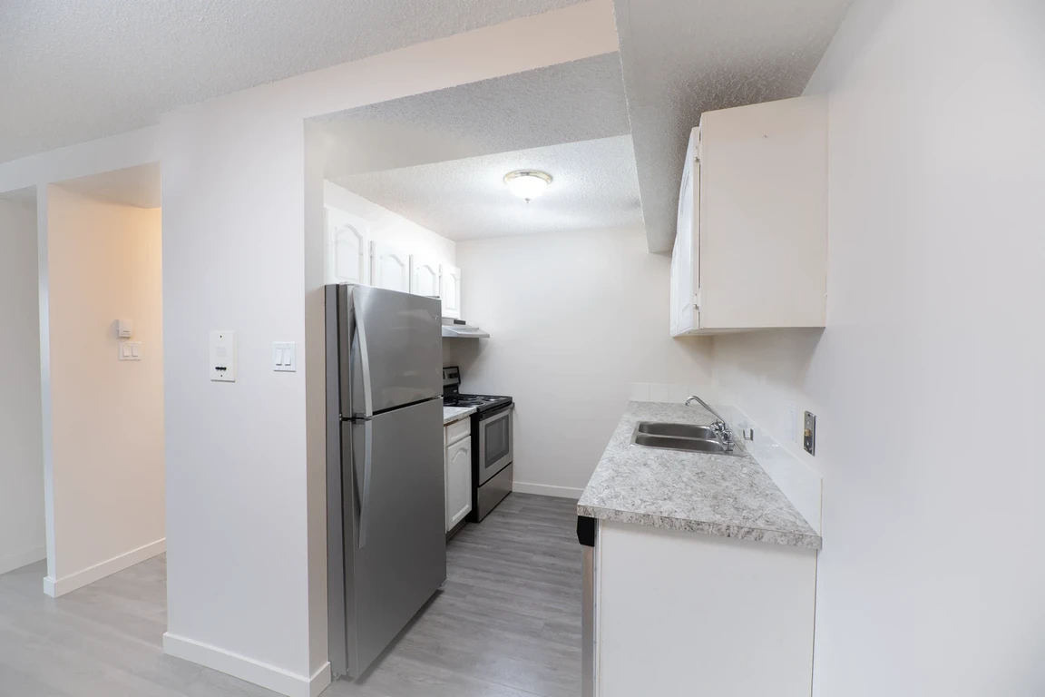 Galley style kitchen with stainless steel appliances at Glenmore Estates in Calgary.