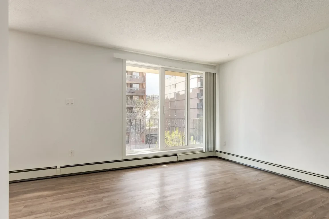 Sunlit living room with large windows at The Winston in Calgary. 