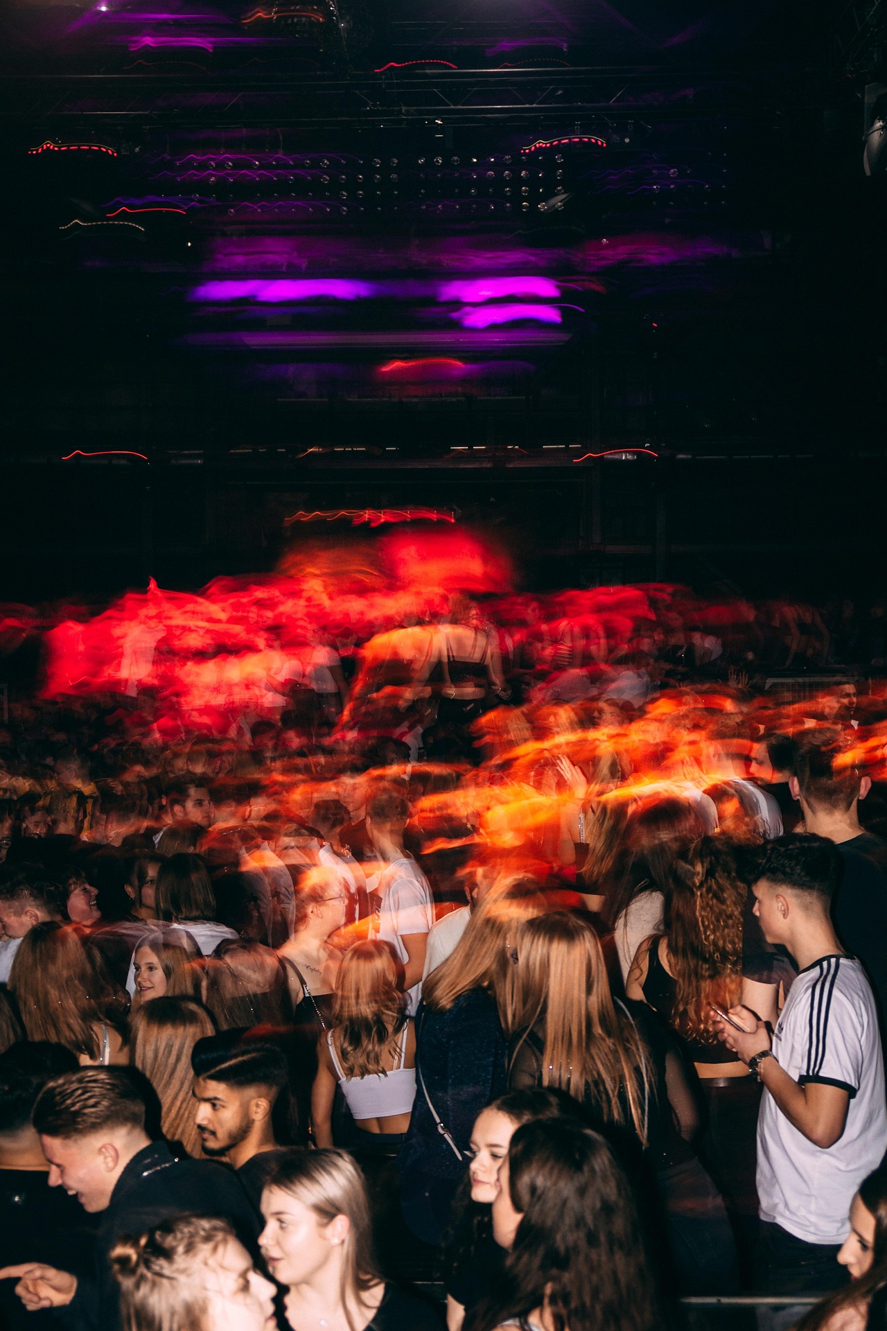 Neon‑lit night out: a packed dance floor moves in a blur of colour and energy under purple stage lights.