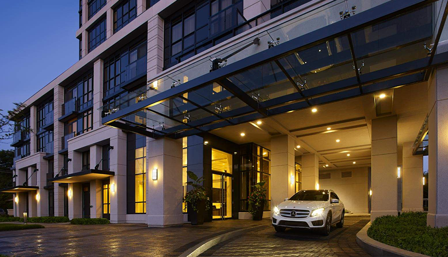 Front Entrance of luxury rental building at 305 Roehampton Avenue with white car at Dusk owned by KG Group