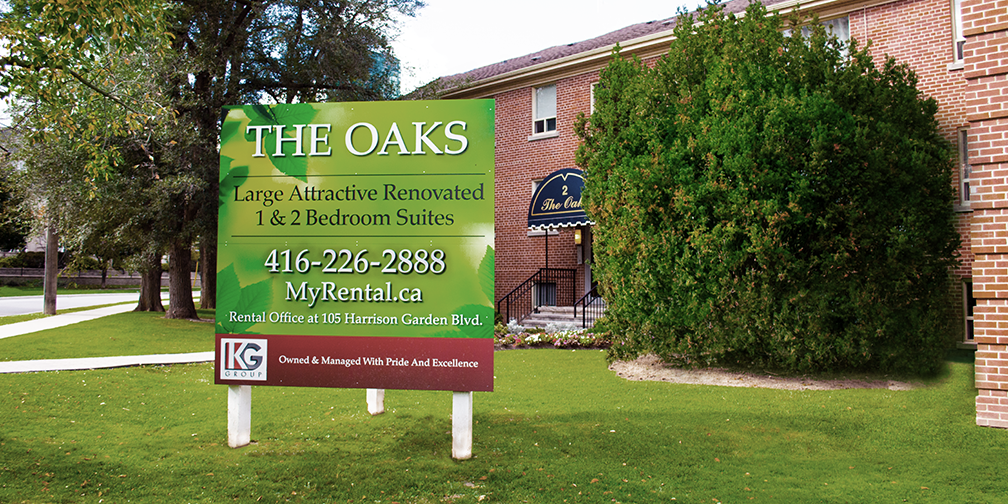 KG Group The Oaks green rental sign with contact information in front of 2-12 Oakburn Crescent apartment buildings in Toronto