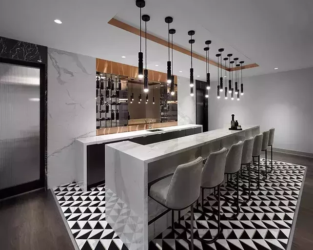 A luxurious bar with white marble finishes and high top chairs for socializing in a premium rental apartment building.