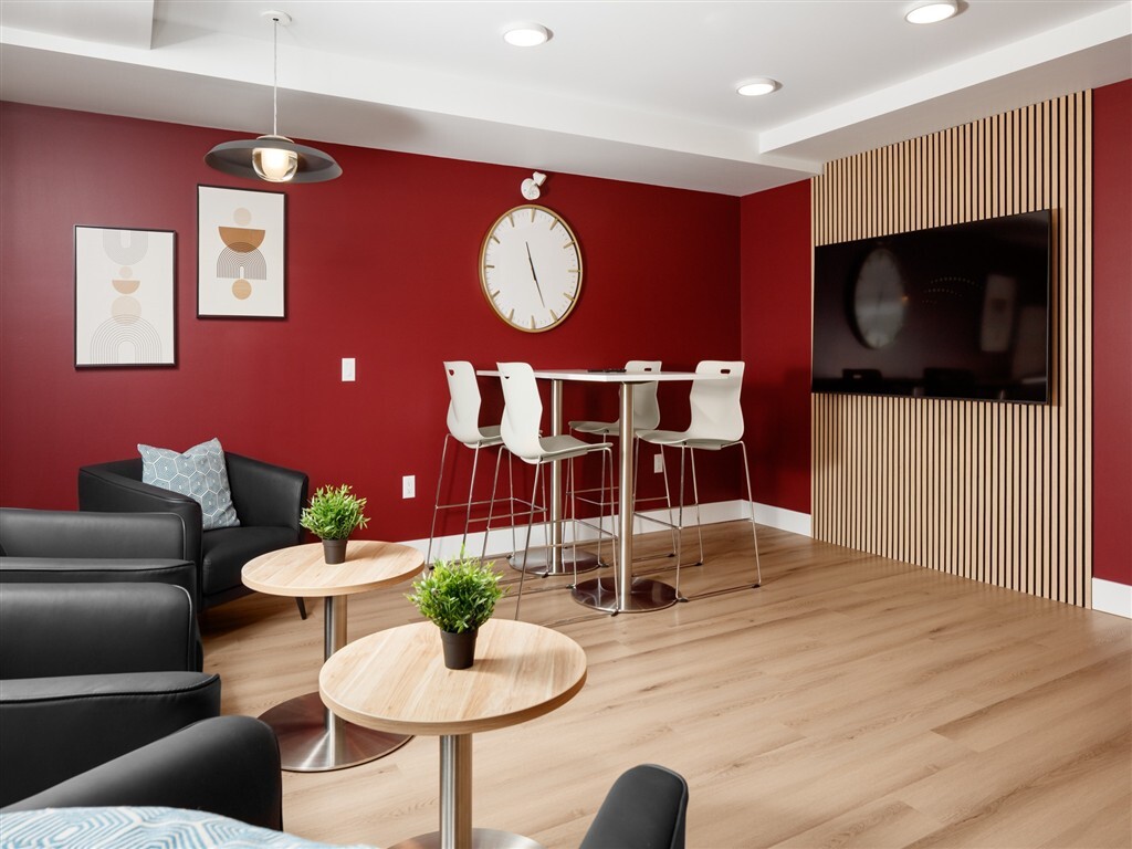 A living room with a red wall and a wooden floor.