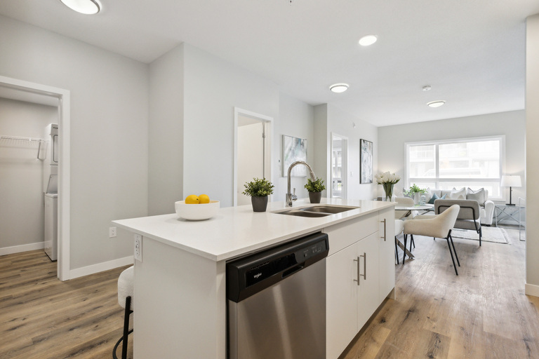 A modern kitchen with white cabinets and a wooden floor.