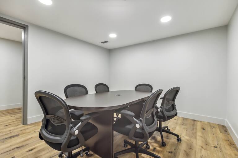 A conference room with a round table and eight chairs.