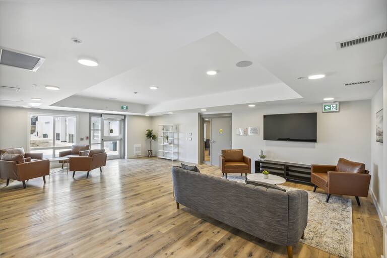 A spacious waiting room with a grey couch and brown chairs.