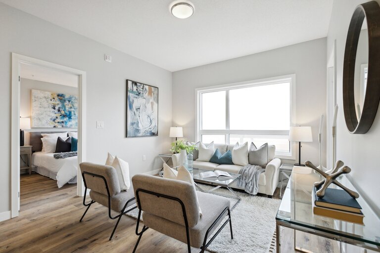 A living room with a white couch and a painting on the wall.