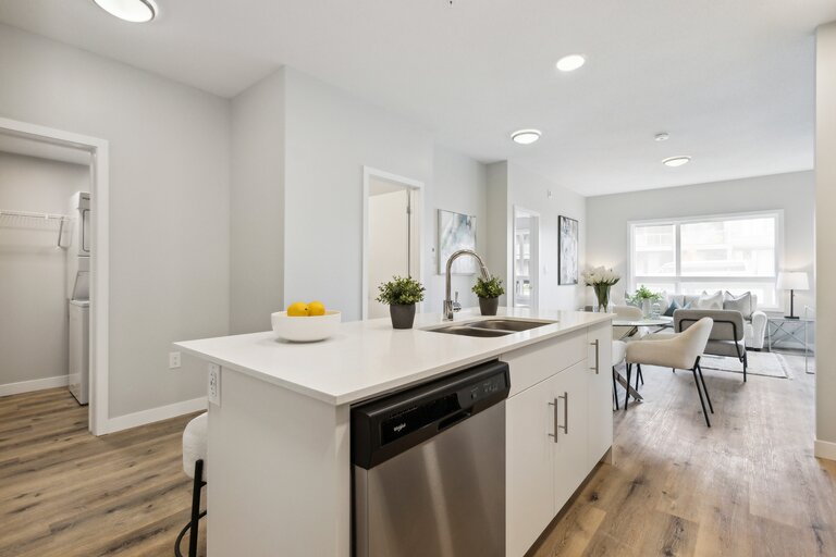 A modern kitchen with white cabinets and a wooden floor.