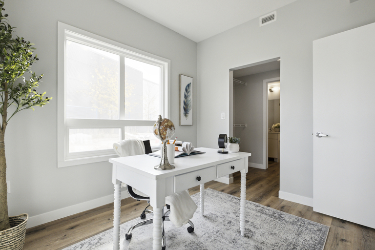 A white desk with a chair and a plant in a room.