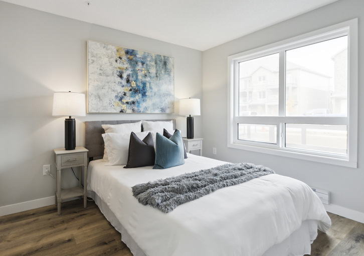 A bedroom with a large bed, two lamps, and a painting on the wall.