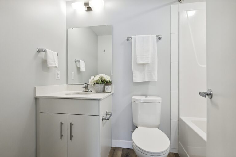 A white bathroom with a toilet, sink, and mirror.