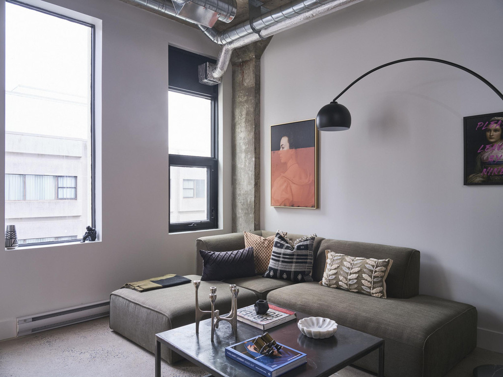 A green sectional couch in a living room with exposed concrete and architectural details.