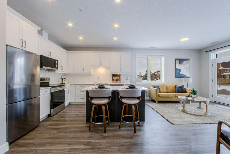Front shot of an open-concept kitchen of a 2-bedroom suite with stainless steel appliances