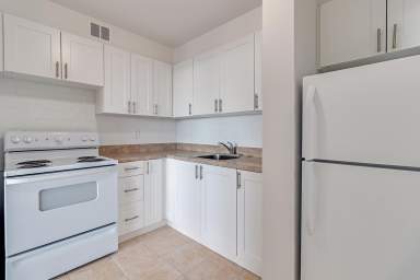 Toronto apartment with sizeable kitchen at 190-200 Exbury Road featuring a fridge, stove, and an abundance of cabinet space.
