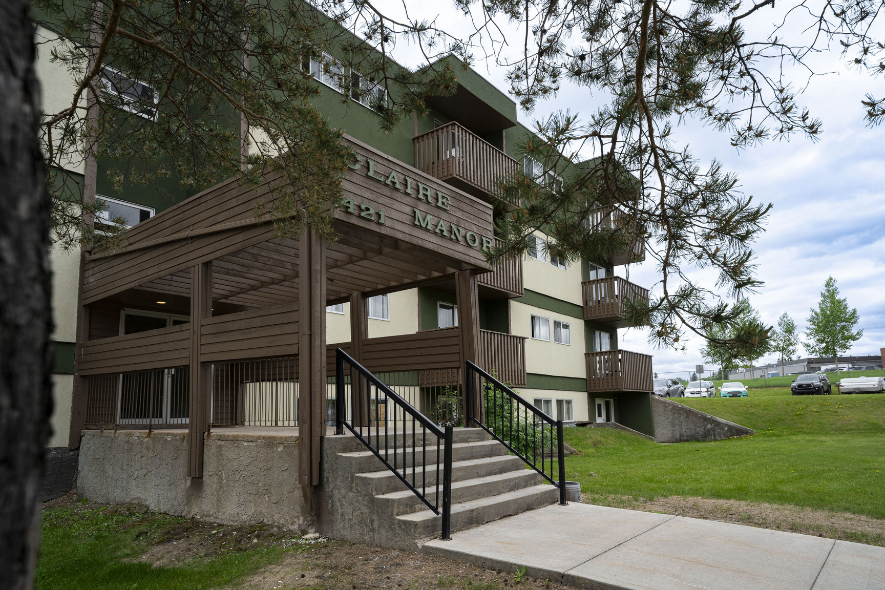 Exterior view of the green and beige four-story Claire Manor apartment complex in Fort McMurray