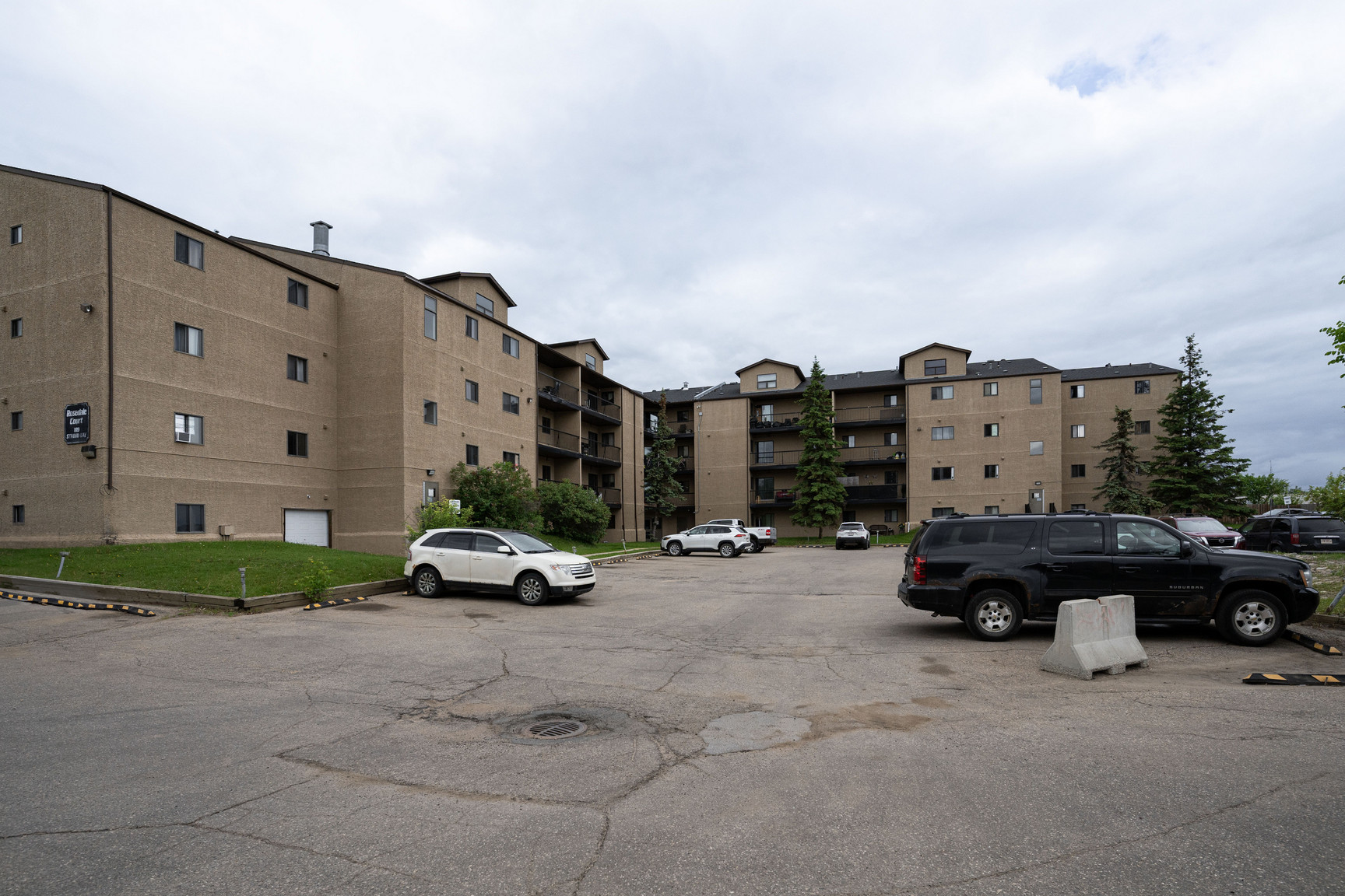 Rosedale Court rental apartments in Fort McMurray showing building exterior, secure entryway, and evergreen trees