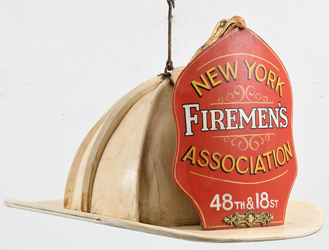 This helmet is made of wood with the New York Firemen’s Association shield. 48th & 18 St.